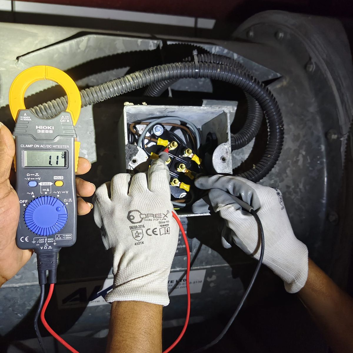 Winsteam technician testing motor terminals with a clamp meter during commissioning